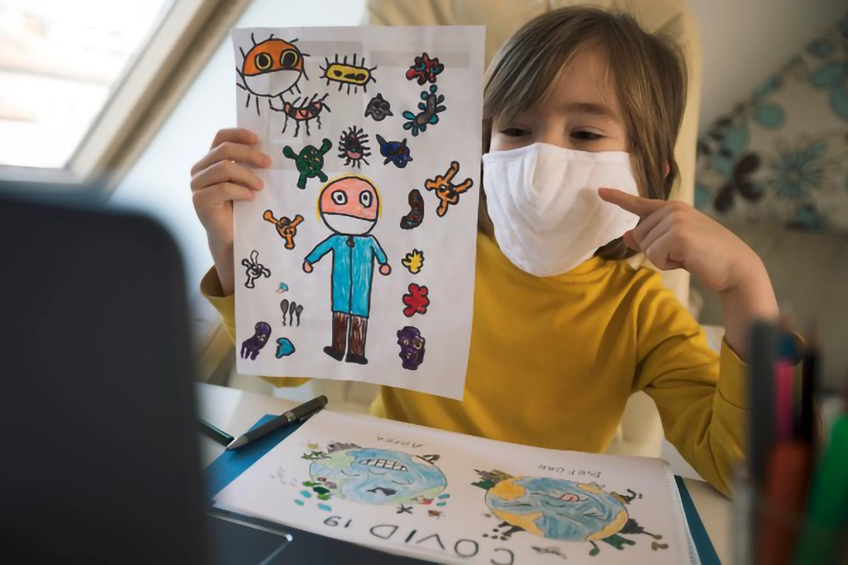 Image of a kid showing a drawing wearing a mask